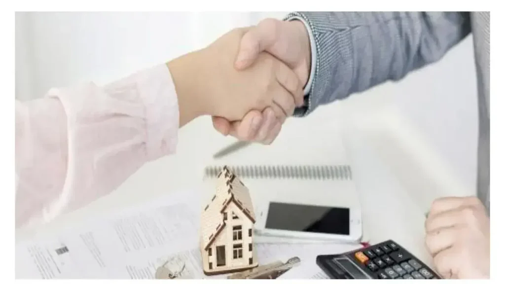 Comprador y agente cerrando un acuerdo sobre la tasación de una vivienda con casa a escala, calculadora y documentos
